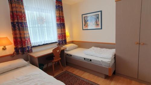 Cette petite chambre comprend deux lits et un bureau. dans l'établissement Lechbruck am See Feriendorf Hochbergle Haus 111, à Lechbruck am See