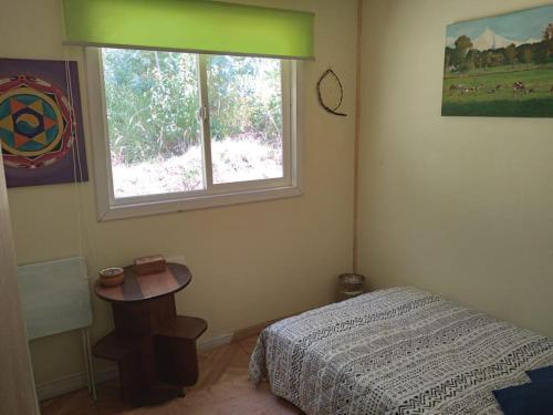 a bedroom with a bed and a table and a window at Donde la Euli in Pitrufquén