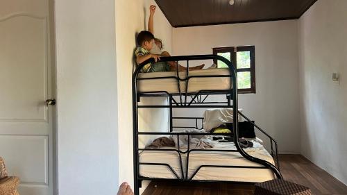 a child is sitting on top of a bunk bed at Finca Ojo de Agua in León