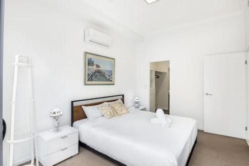 a white bedroom with a white bed and a mirror at Central of Toowong Neat Apt Near Station in Brisbane