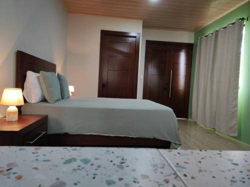 a bedroom with a bed and a nightstand with a lamp at Mandy Loft -40MB wifi -estacionamiento gratuito in San Ramón