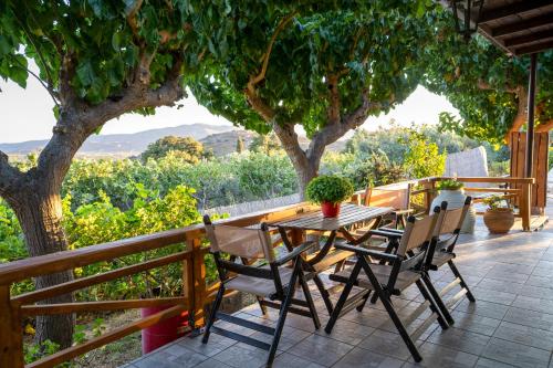 een houten tafel en stoelen op een patio met een boom bij Ktima Asteria in Karistos