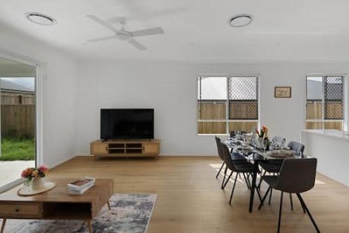 a white living room with a table and a tv at Brandnew 4BR modern family home Park Ridge in Park Ridge