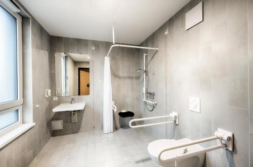 ein Bad mit einer Dusche, einem WC und einem Waschbecken in der Unterkunft B&B HOTEL Wiener Neudorf in Wiener Neudorf