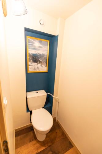 La salle de bains est pourvue de toilettes blanches dans un mur bleu. dans l'établissement Les Montagnettes, aux Orres