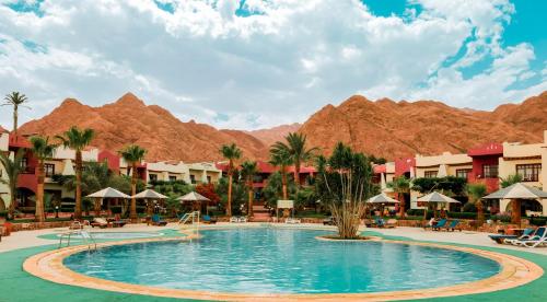 een zwembad in een resort met bergen op de achtergrond bij Tropitel Dahab Oasis in Dahab