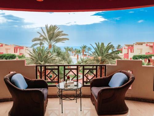 a balcony with two chairs and a glass table at Tropitel Dahab Oasis in Dahab