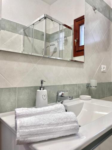 La salle de bains blanche est pourvue d'un lavabo et d'un miroir. dans l'établissement CASA GIULIA - Holiday Home, à Olbia