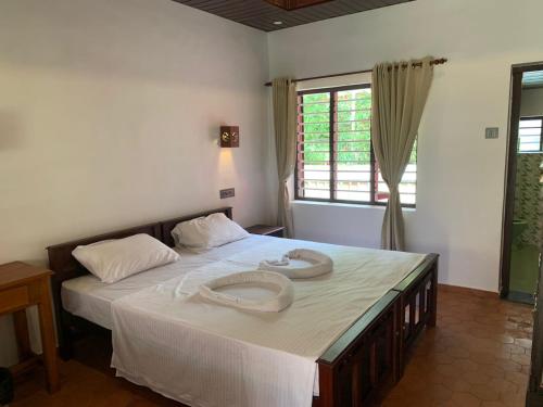 um quarto com uma cama grande e lençóis brancos em Hotel Holiday Home em Kovalam