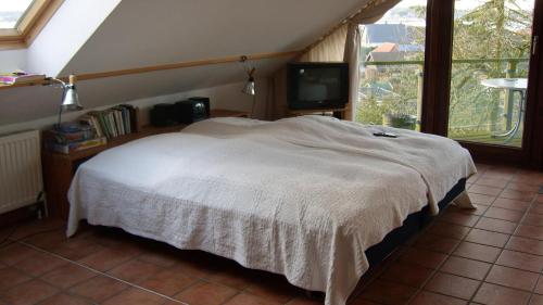 Schlafzimmer mit einem weißen Bett und einem TV in der Unterkunft FeWoFahrdorf in Fahrdorf