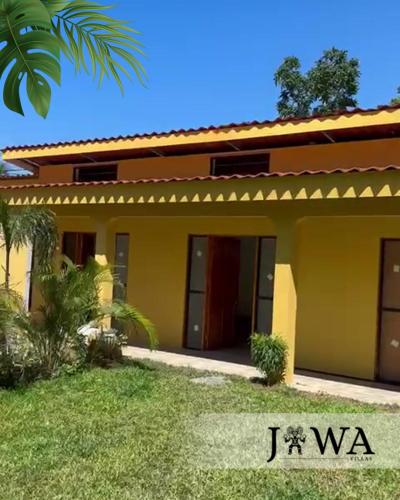 uma casa com uma casa amarela com uma palmeira em Villas Jawa - Cabinas em Puerto Limón