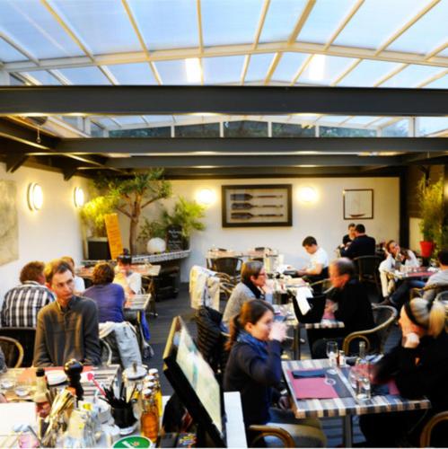 un groupe de personnes assises à des tables dans un restaurant dans l'établissement Hôtel Restaurant Corto Maltese, au Palais