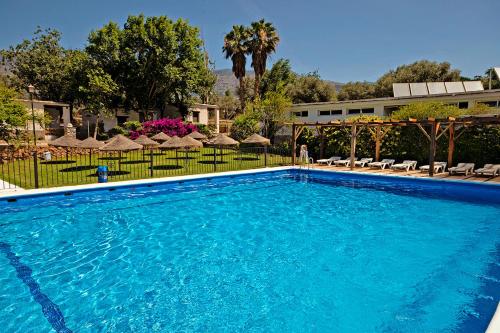 una gran piscina azul con sombrillas y un edificio en Camping Orgiva, en Órgiva