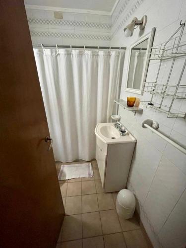 een badkamer met een wit douchegordijn en een wastafel bij Verona Cabaña in Necochea