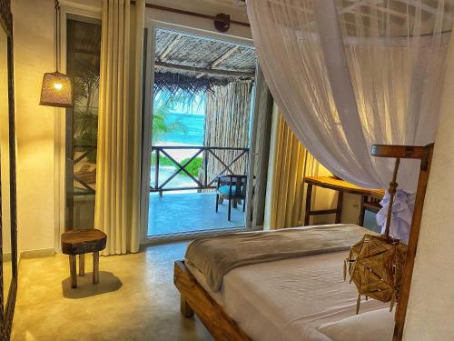 a bedroom with a bed and a view of the ocean at Infinity Beach Boutique Hotel & SPA in Matemwe