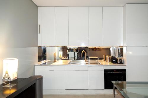 une cuisine avec des armoires blanches et un évier dans l'établissement Loft atypique avec terrasse, calme et cosy, à Paris