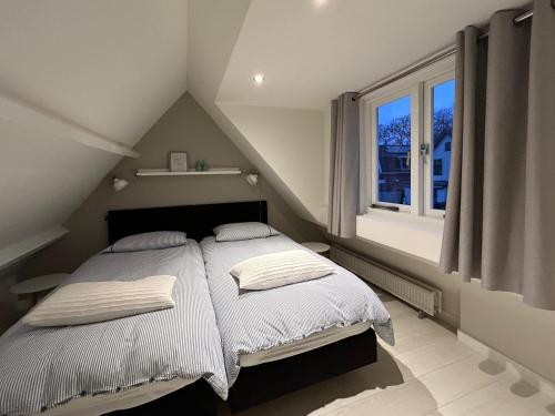 una camera da letto con un letto con lenzuola bianche e una finestra di Appelbloesem a Bergen