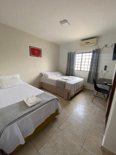 a bedroom with two beds and a desk with a chair at Pousada Flor De Brasília in Brasilia