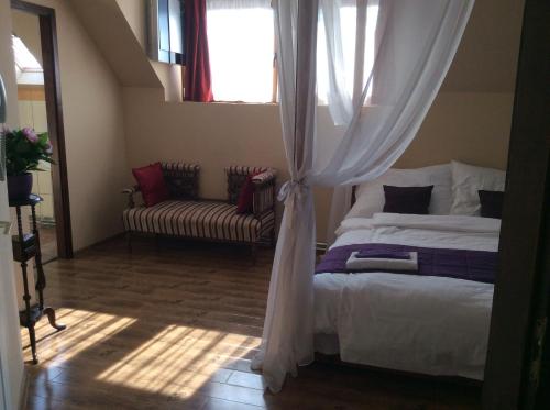 a bedroom with a bed and a window and a couch at Abszolút Hotel és Panzió in Nyírbátor