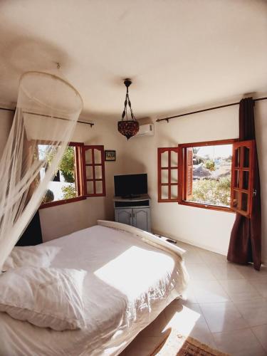 1 dormitorio con 1 cama blanca y 2 ventanas en Menzel Caja en Aghīr