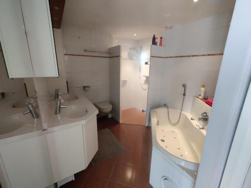 a white bathroom with two sinks and a toilet at B&B De Slaperije in Warnsveld
