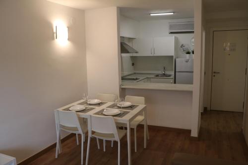 a white dining room table with white chairs and a kitchen at MyF Michelangelo sun in Salou