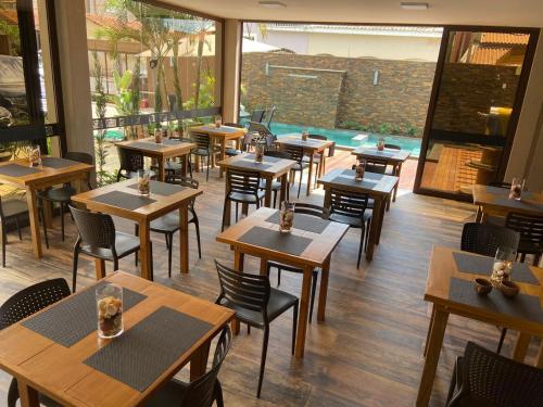 un restaurant avec des tables et des chaises en bois et une piscine dans l'établissement POUSADA MALA E CUIA, à Rifaina