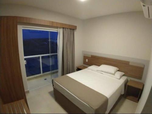 - une chambre avec un lit et une grande fenêtre dans l'établissement Eco Resort Ilhas do Lago, à Caldas Novas
