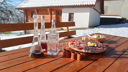 - une table en bois avec deux bouteilles et une assiette de nourriture dans l'établissement Grunt Sonek, à Mislinja