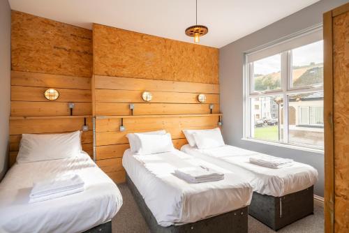 two twin beds in a room with a window at Riverside by Afan Valley Escapes in Glyncorrwg