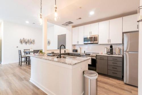 uma grande cozinha com armários brancos e uma bancada em Cozy Apartment with WiFi em Charlotte