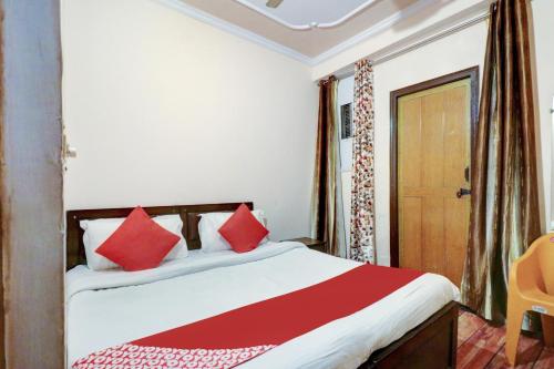 a bedroom with a bed with red pillows and a door at Ratiram Hotel Near Worlds of Wonder in Kalkaji Devi