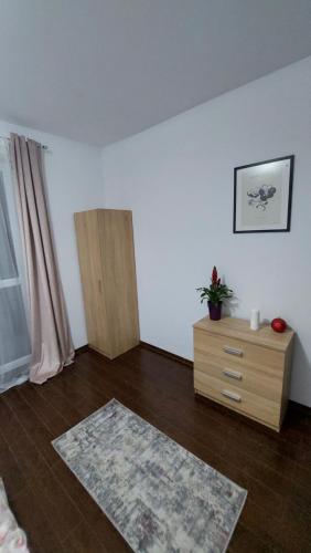 a room with a white wall and a wooden dresser at Apartament Râșnov in Râşnov
