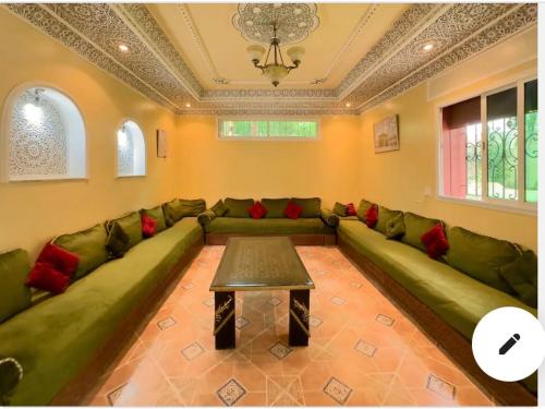a living room with a green couch and a table at Villa calme a tamuda bay médique region de tetuan in M'diq