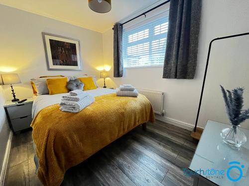 a bedroom with a bed with yellow pillows and a window at Stylish Bungalow near M42, HS2, Airport, NEC & JLR in Sheldon