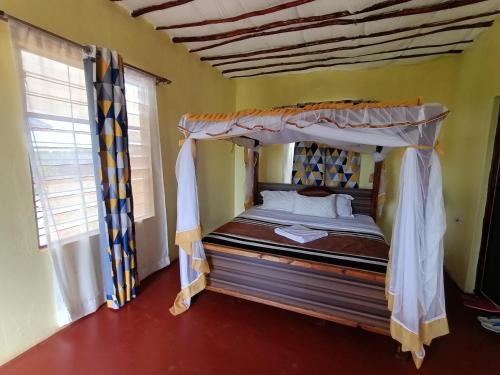 a bedroom with a canopy bed in a room with windows at Tausa Tsavo Eco Lodge in Voi