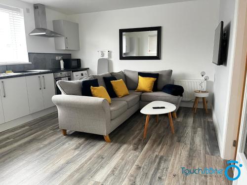 a living room with a gray couch and yellow pillows at Stylish Bungalow near M42, HS2, Airport, NEC & JLR in Sheldon