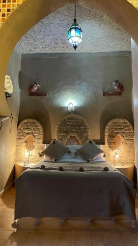 a bedroom with a large bed in a stone room at Riad Dar Poublanc in Merzouga