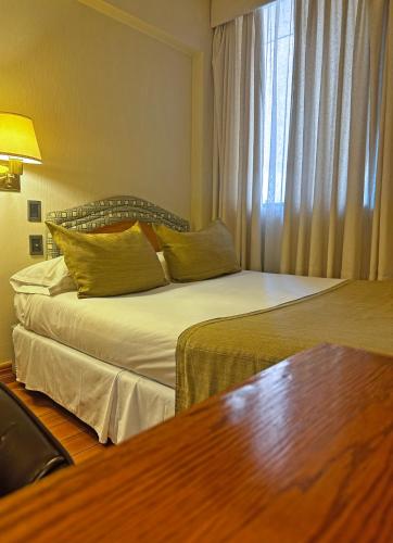 a hotel room with two beds and a table at Hotel Frontera Clásico in Temuco
