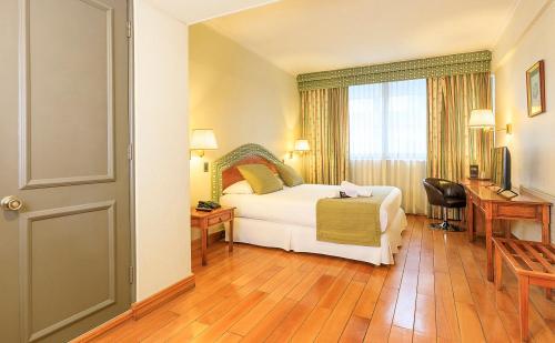 a hotel room with a bed and a desk and a window at Hotel Frontera Clásico in Temuco