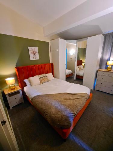 a bedroom with a large bed with a red headboard at 3 Bed House Etihad in Manchester