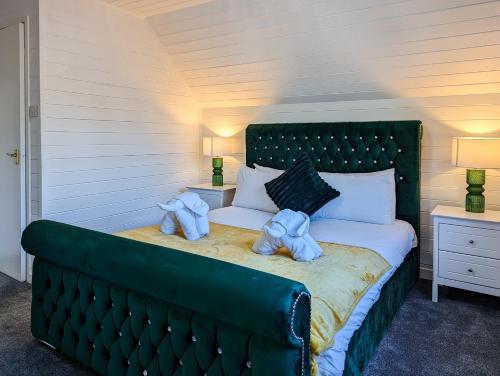 Un dormitorio con una cama verde con toallas. en Morrigan 7-Hot Tub-Pet Friendly-Boutique-Perthshire-Families en Perth