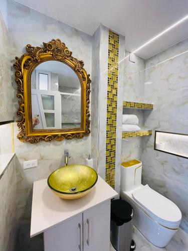 a bathroom with a gold sink and a toilet at Hostal Balcon del Cielo in Baños