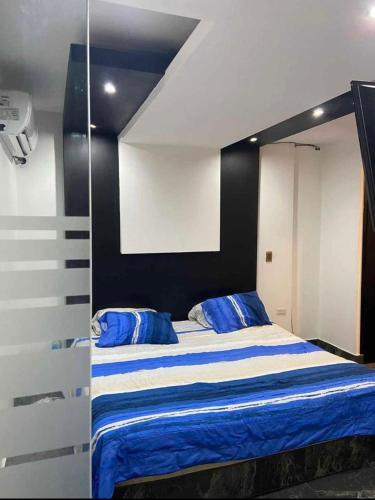 Schlafzimmer mit einem Bett mit blauer und weißer Bettwäsche in der Unterkunft Departamentos Alex in Cuauhtémoc