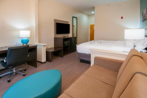 a hotel room with a bed and a couch and a tv at Sleep Inn & Suites in Tuscaloosa