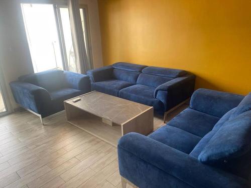ein Wohnzimmer mit einem blauen Sofa und einem Couchtisch in der Unterkunft Spacieux F4 confort et modernité in Dakar