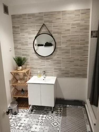 a bathroom with a sink and a mirror on a wall at Maison Diana à 400 mètres à pieds de l'aéroport in Tillé