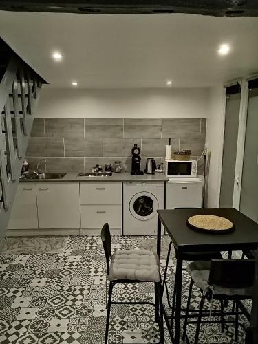uma cozinha com uma mesa, um lavatório e um fogão em Maison Diana à 400 mètres à pieds de l'aéroport em Tillé