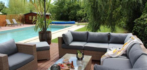 eine Terrasse mit Sofas, einem Tisch und einem Pool in der Unterkunft Le Mas Charamèlia in Saint-Victor-de-Malcap