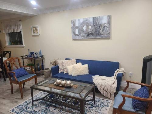 uma sala de estar com um sofá azul e cadeiras em 2 Bedroom East-York bungalow em Toronto